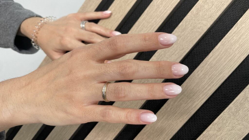 Manicura semipermanente en tono nude sobre fondo de listones de madera